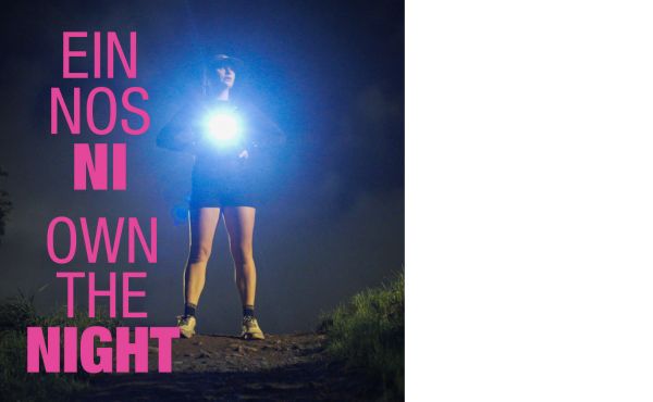 Photo of a woman runner wearing a chest torch at night with the words 'ein nos ni' 'own the night' in pink text
