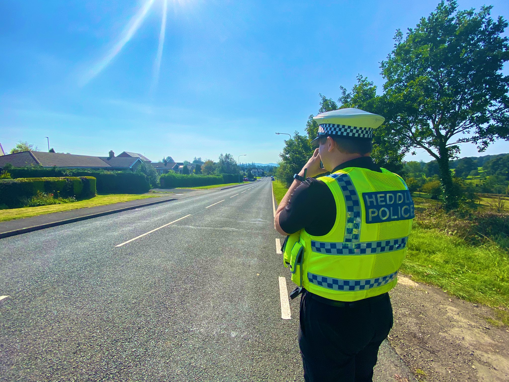 Police officer in high visibility jacket carrying out a speed check on a rural road. 