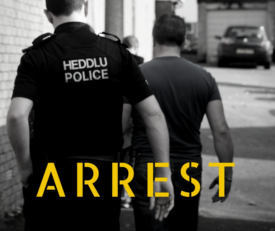 Police officer and person walking away from the camera with word arrest in yellow across bottom