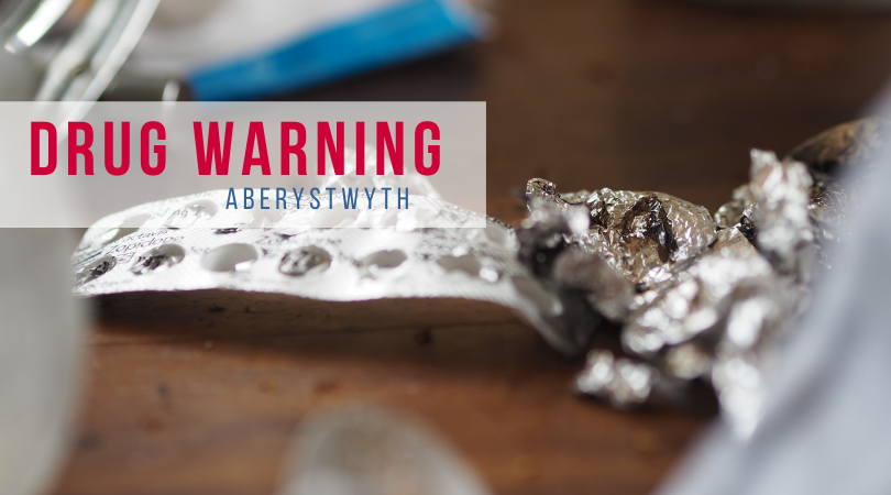 Llun o gyffuriau, ac offer cyffuriau, gyda'r geiriau "rhybudd cyffuriau - Aberystwyth"