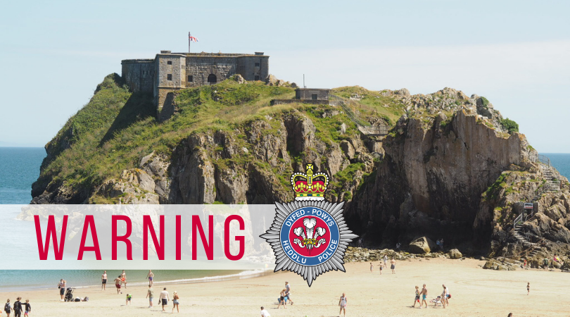 Stock image of Tenby beach, with warning written in red text over a white banner