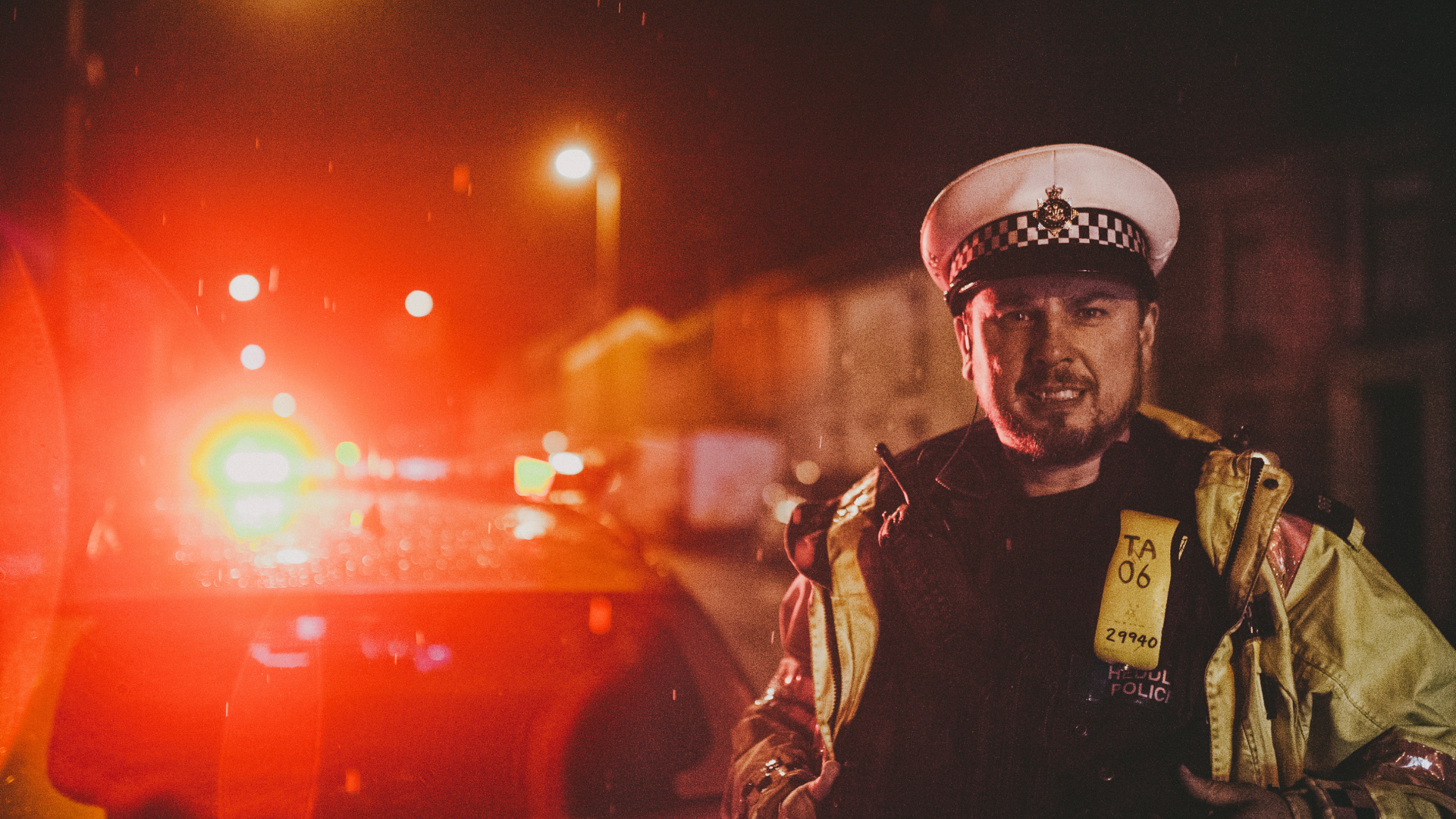 Officer in darkness with police car lights flashing